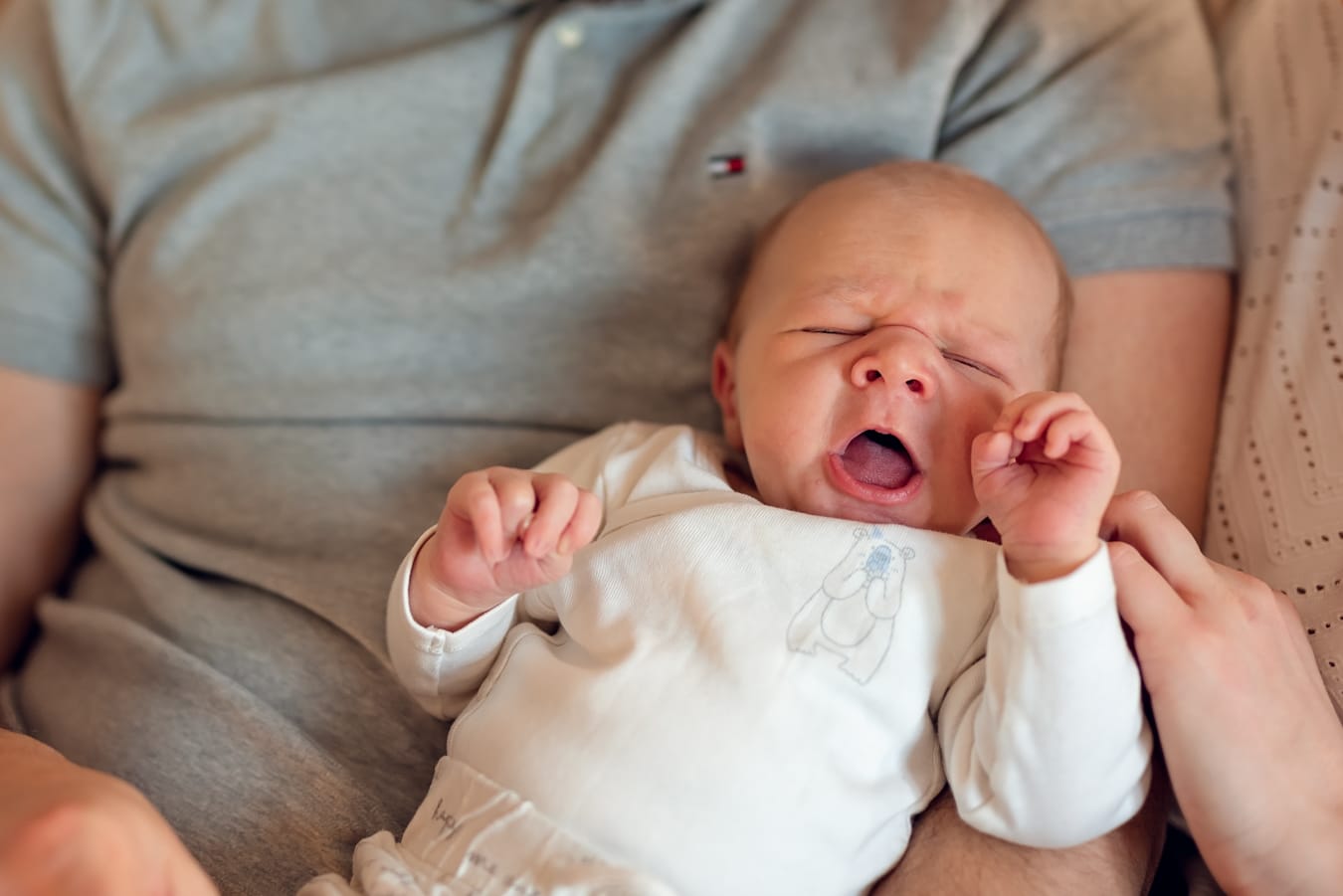 Ziewający noworodek w ramionach taty sesja w domu Gdańsk