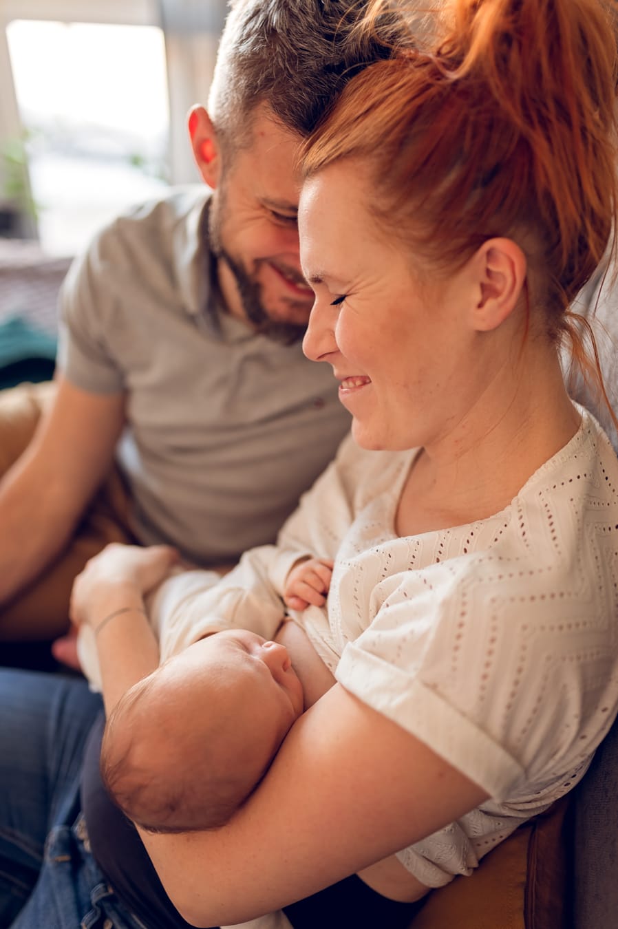 Roześmiani rodzice z noworodkiem sesja w domu Gdańsk