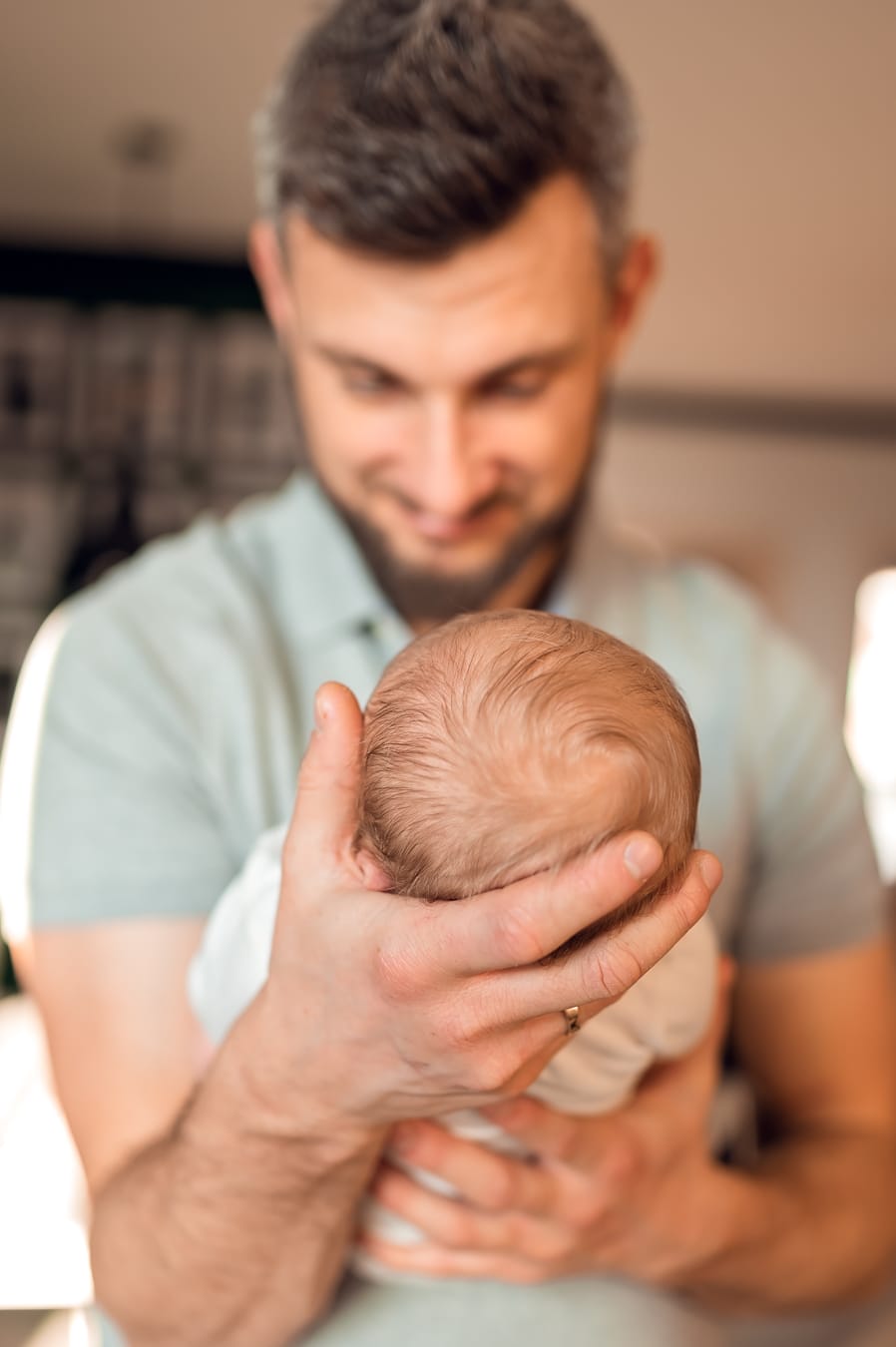 Tata patrzy na noworodka sesja z noworodkiem w domu Gdańsk