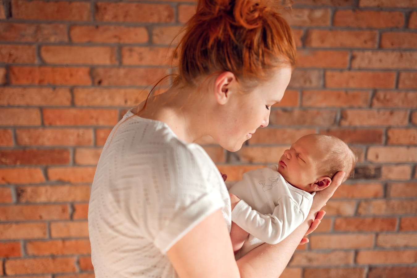 Mama patrzy na noworodka w dłoniach sesja Gdańsk