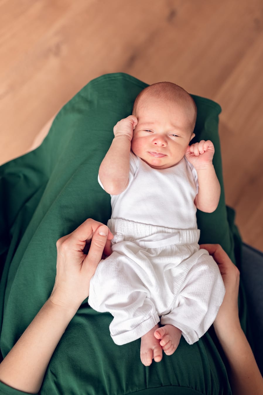 Noworodek leżący na kolanach mamy rodzinna sesja noworodkowa Trójmiasto