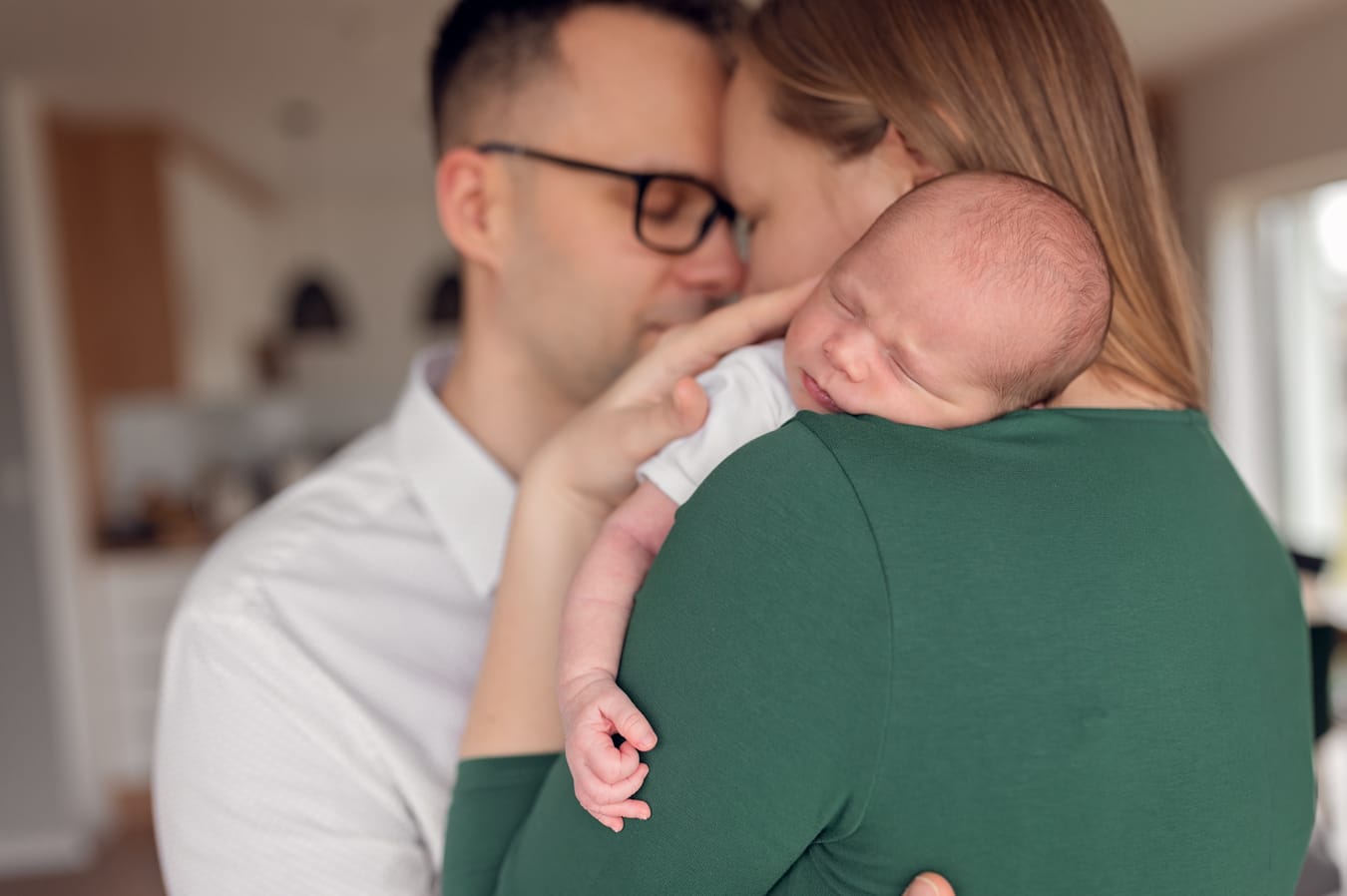 Śpiący noworodek w ramionach rodziców sesja w domu