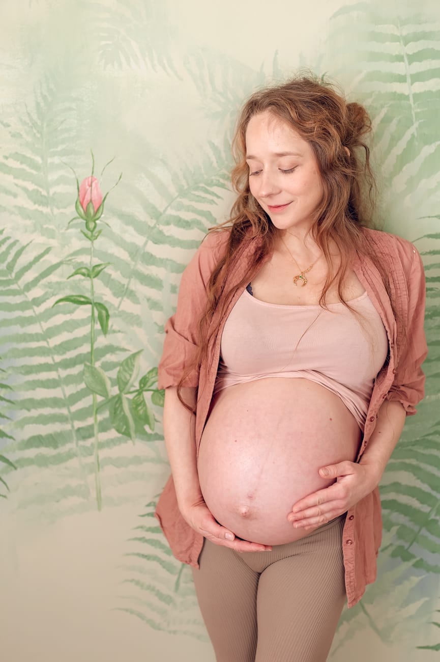 Mama w ciąży na tle róży na ścianie sesja Gdańsk