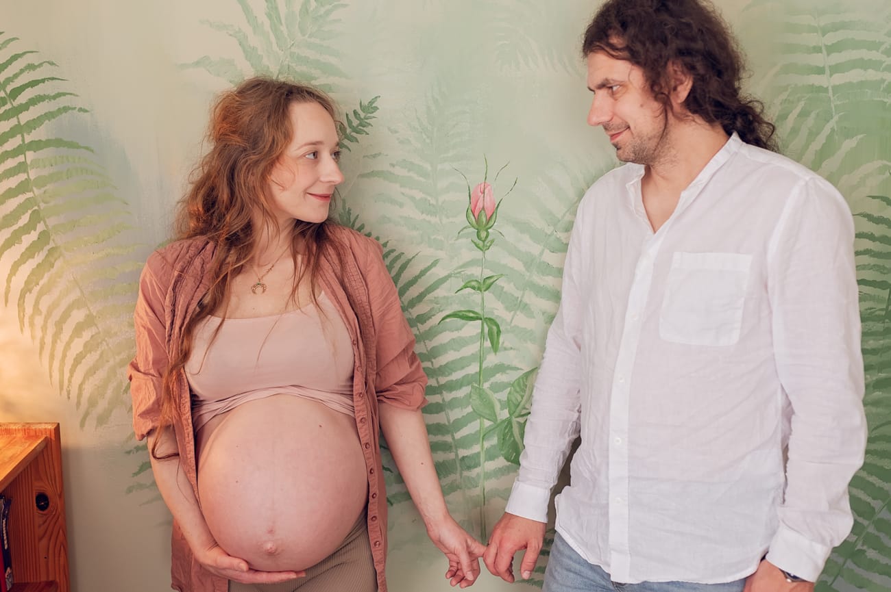 Para na tle róży na ścianie sesja ciążowa w domu