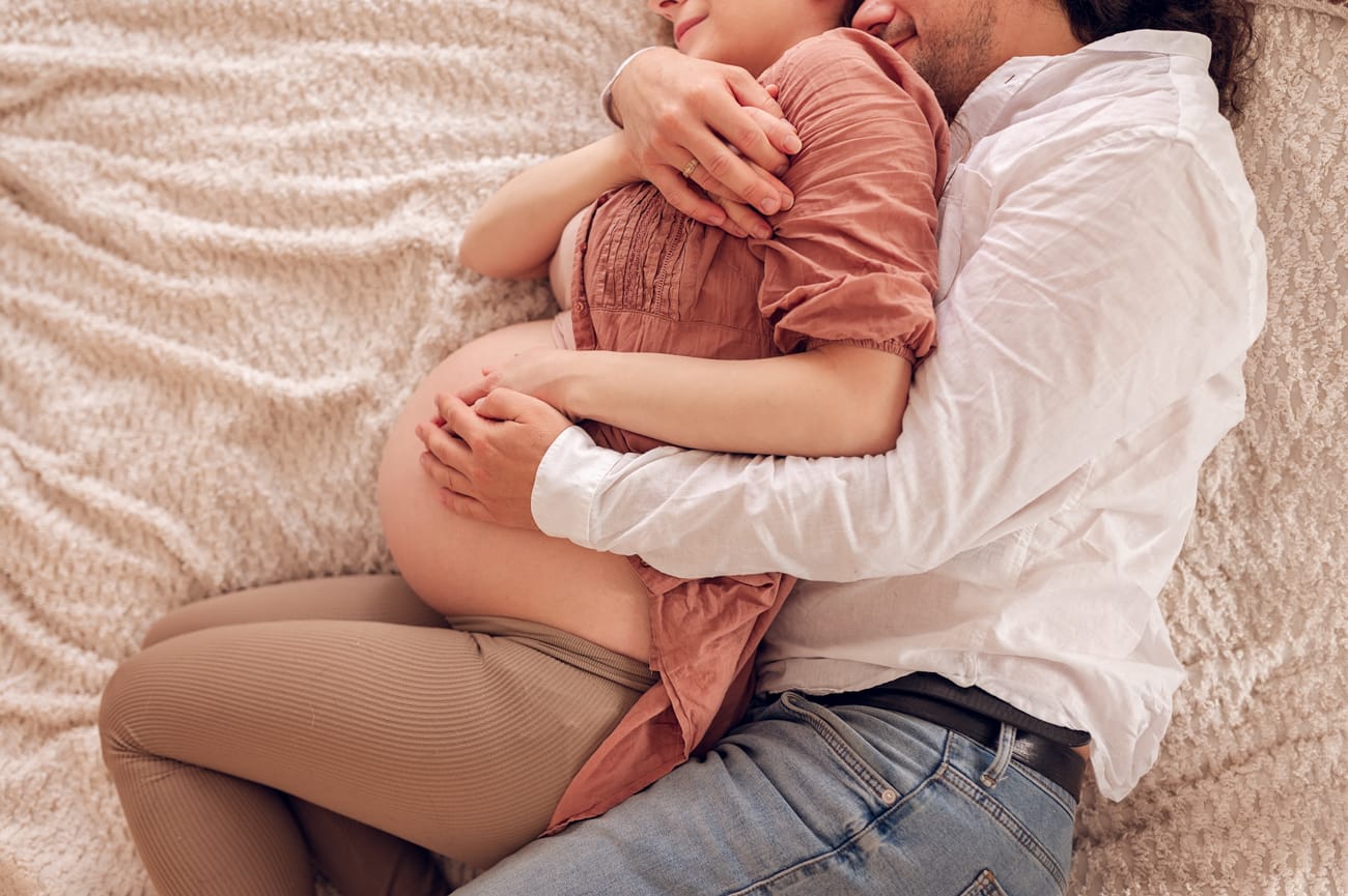 Para na łóżku brzuszek sesja ciążowa w domu