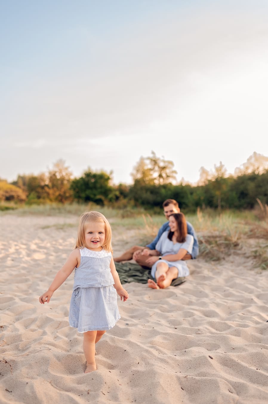 Dziewczynka biegnie rodzice w tle sesja nad morzem