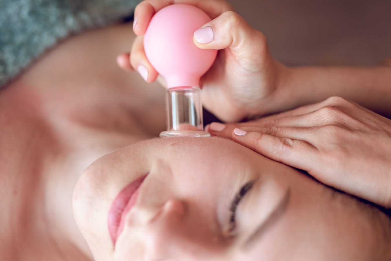 Terapeutka wykorzystuje bańki chińskie do masażu twarzy, poprawiając krążenie i redukując napięcie mięśniowe.
