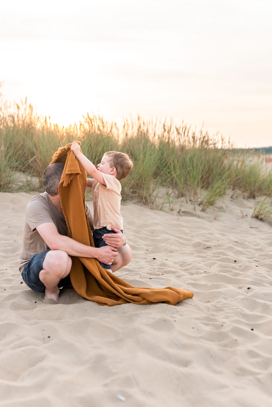 Syn zasłania tatę kocem zabawy sesja nad morzem