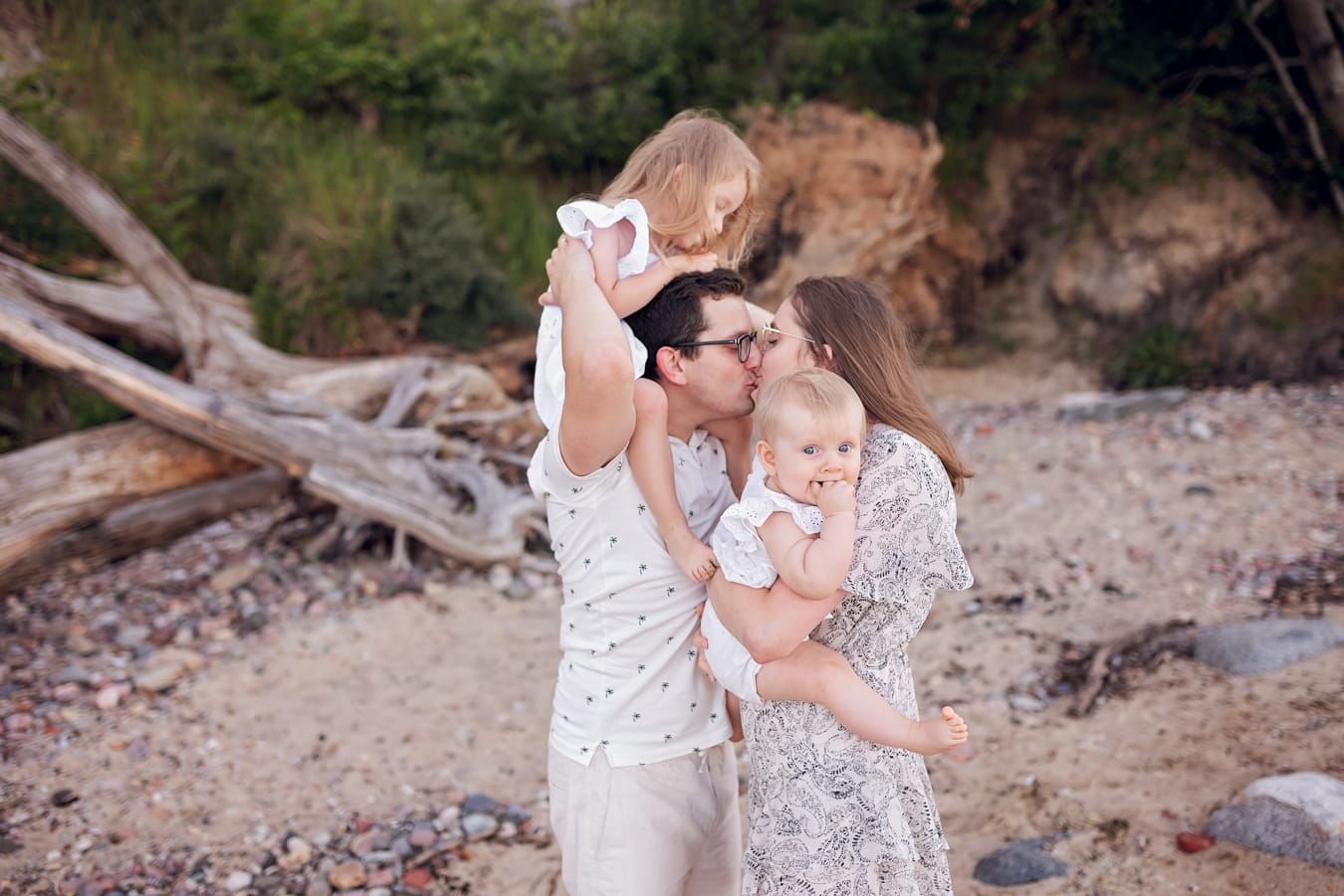 Rodzice całują się z dziećmi w ramionach sesja nad morzem Gdynia