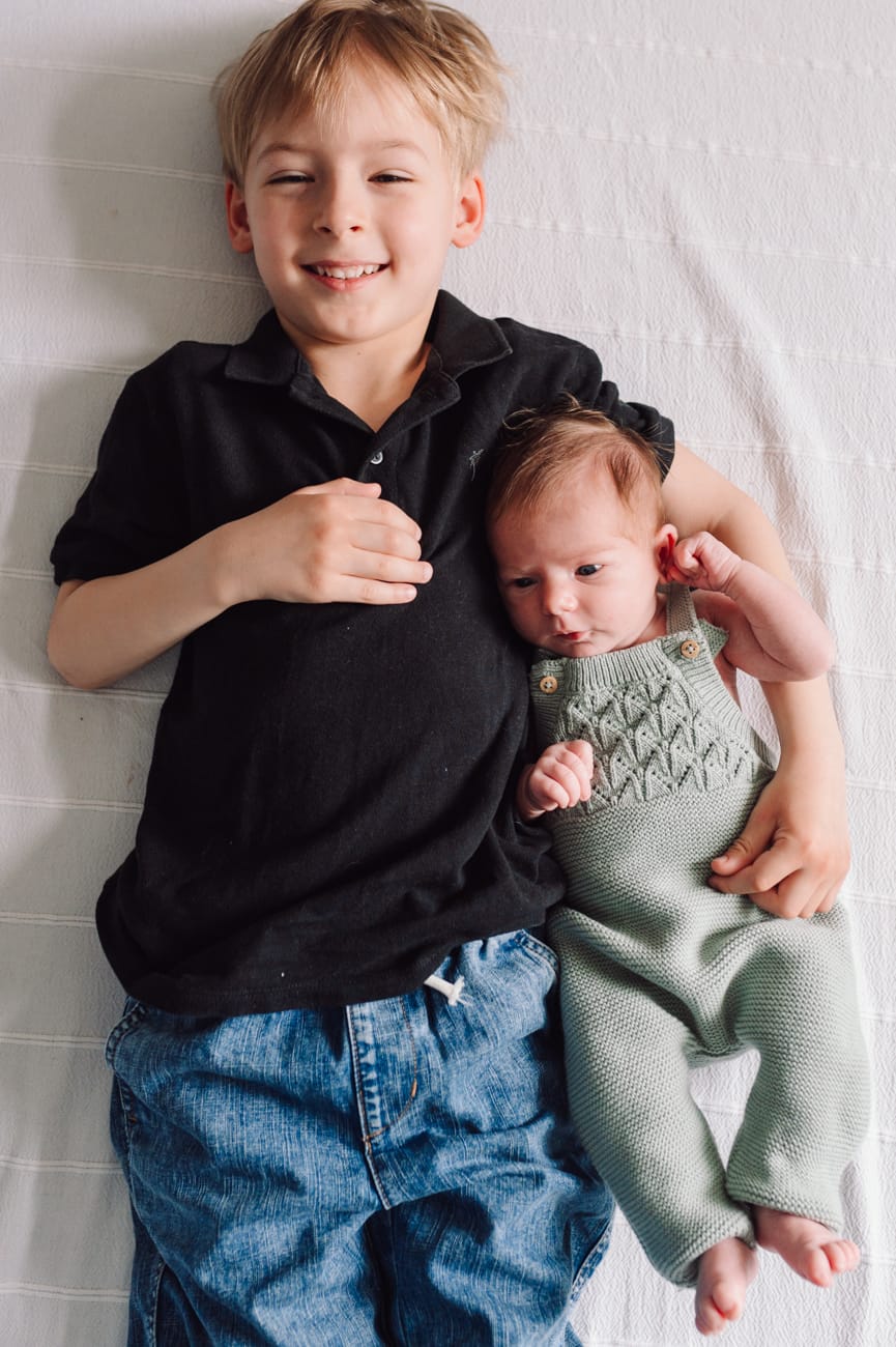 Starszy i młodsza siostra podczas sesji noworodkowej lifestyle