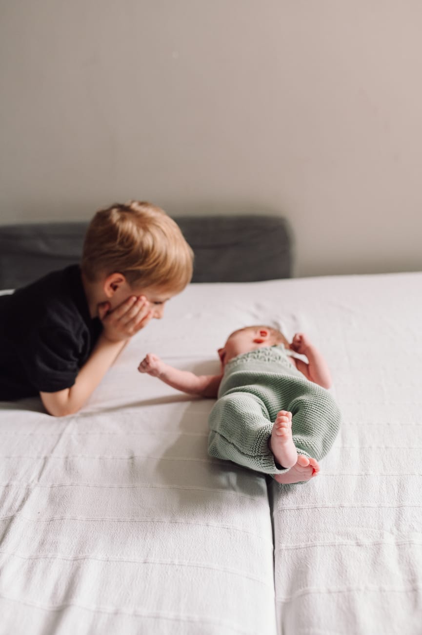 Starszy brat wita noworodka sesja mama z dziećmi w domu