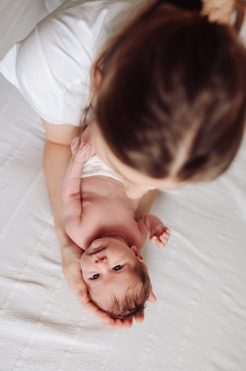 Mama z noworodkiem na łóżku sesja noworodkowa w domu