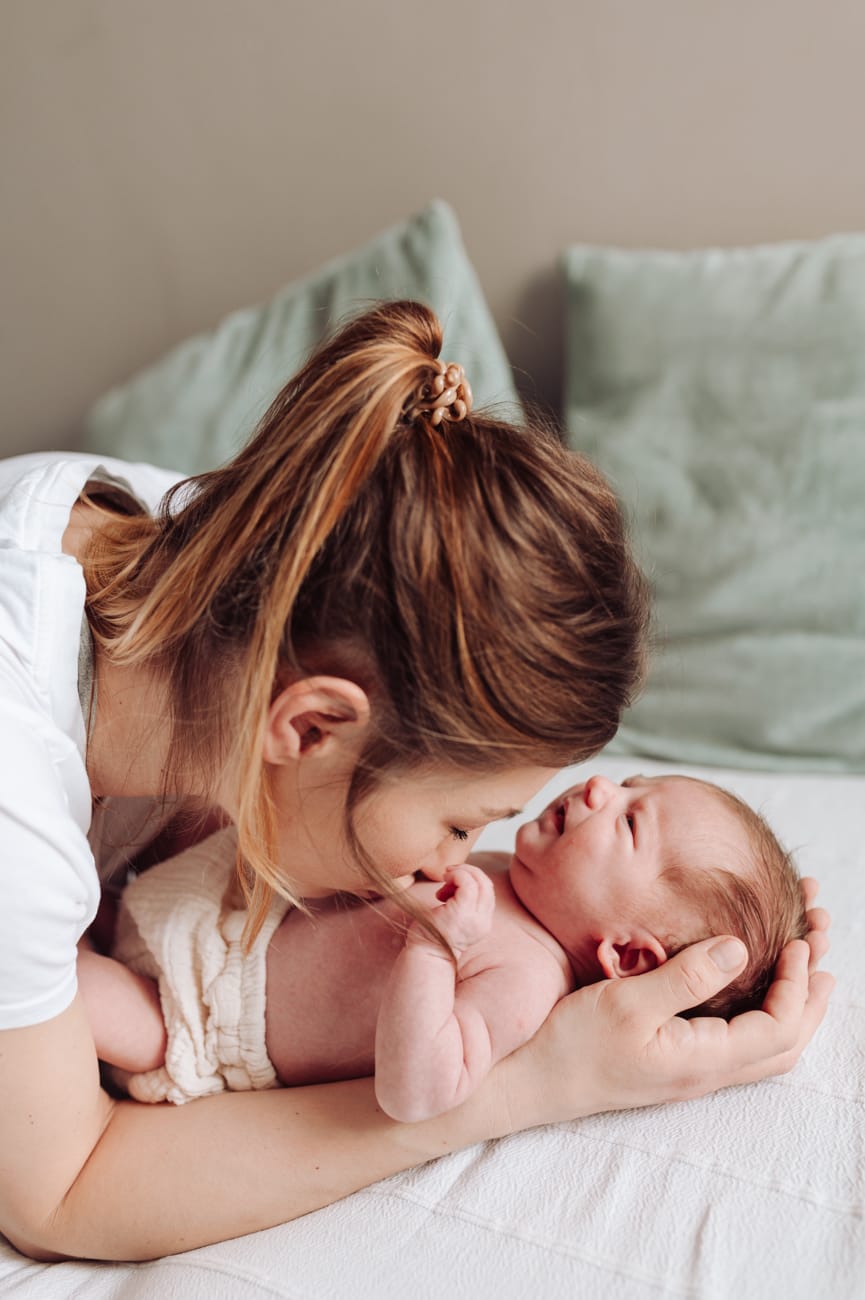 Mama całuje brzuszek noworodka sesja noworodkowa