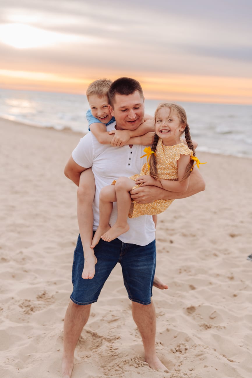 Tata trzyma dwoje dzieci zachód słońca sesja rodzinna