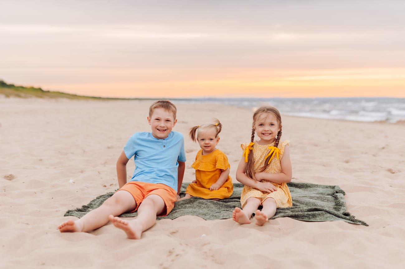Trójka dzieci na kocu na plaży sesja w wakacje Gdańsk