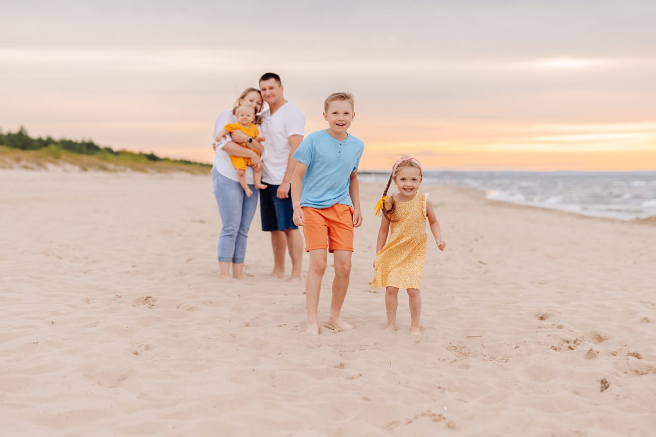 Dzieci śmieją się rodzice przytuleni w tle sesja wakacyjna