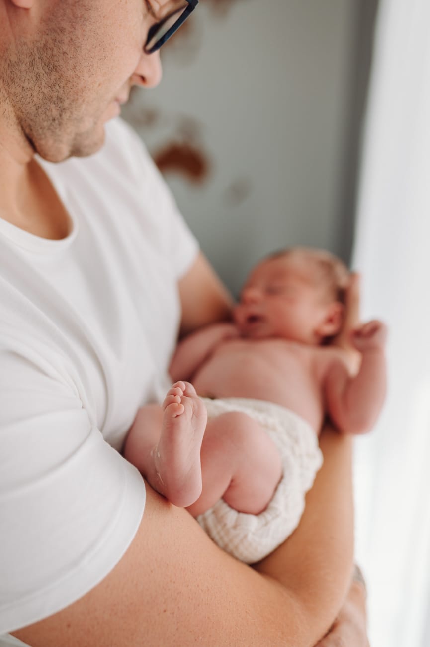 Stópka noworodka w dłoni rodzica sesja w domu Gdynia
