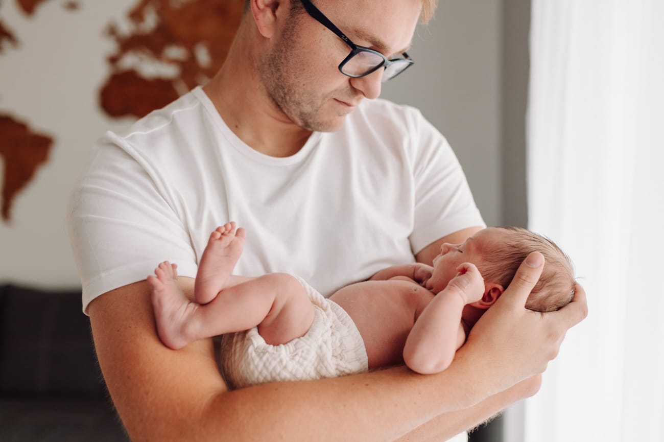 Tata trzyma noworodka sesja noworodkowa w domu Gdynia
