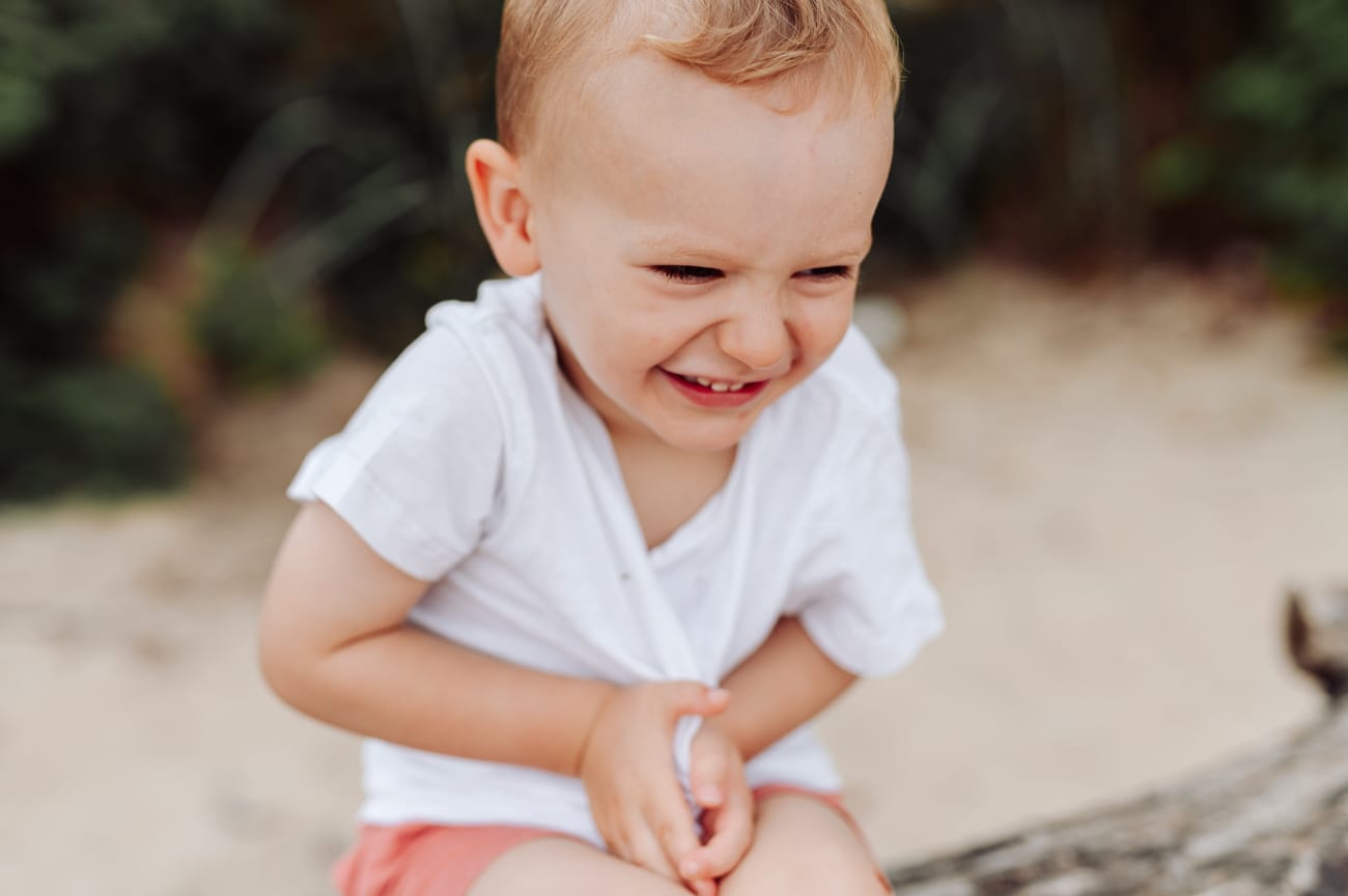 Roześmiany chłopiec na drzewie na plaży sesja rodzinna Gdynia