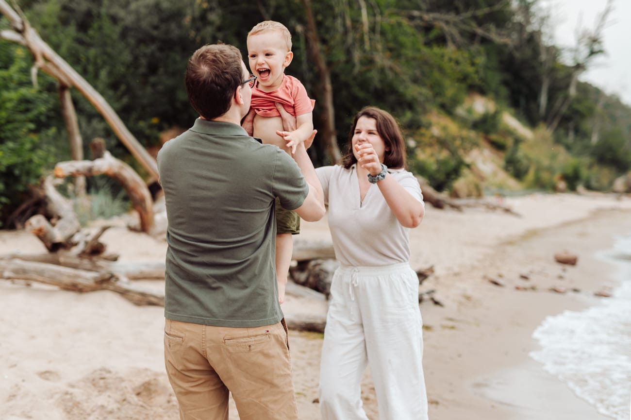 Rodzice podrzucają dwulatka na plaży sesja rodzinna