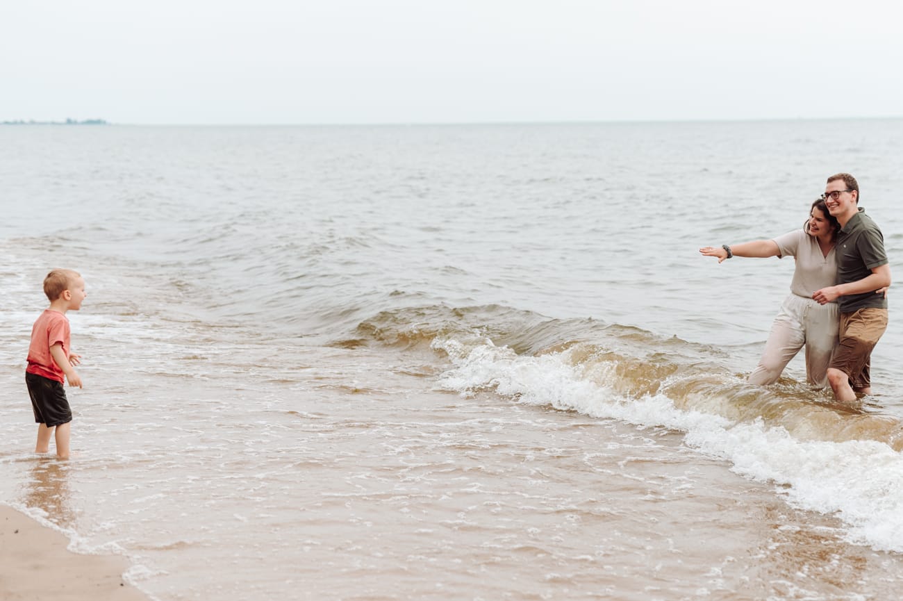 Rodzice zachęcają dwulatka do wody sesja nad morzem