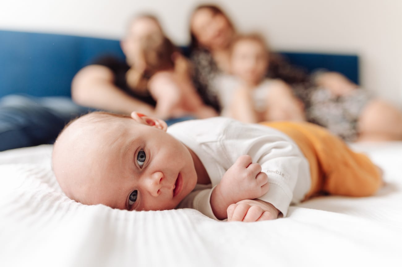 Niemowlę na łóżku rodzina w tle sesja w domu Gdańsk