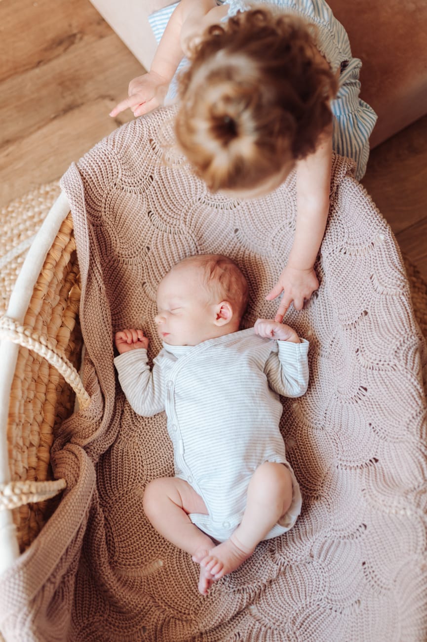 Siostra dotyka noworodka sesja noworodkowa z rodzeństwem Gdańsk