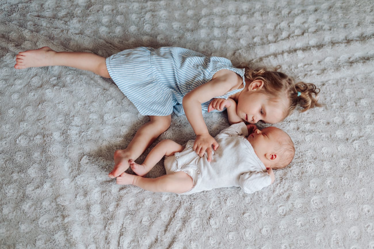 Siostra i noworodek na łóżku sesja z rodzeństwem Gdańsk