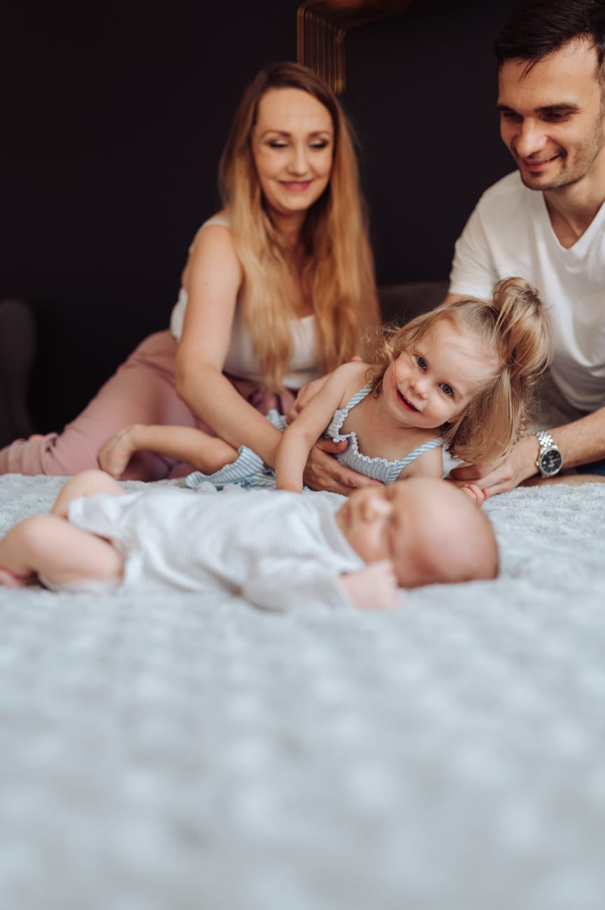 Siostra zagląda do śpiącego noworodka sesja z rodzeństwem