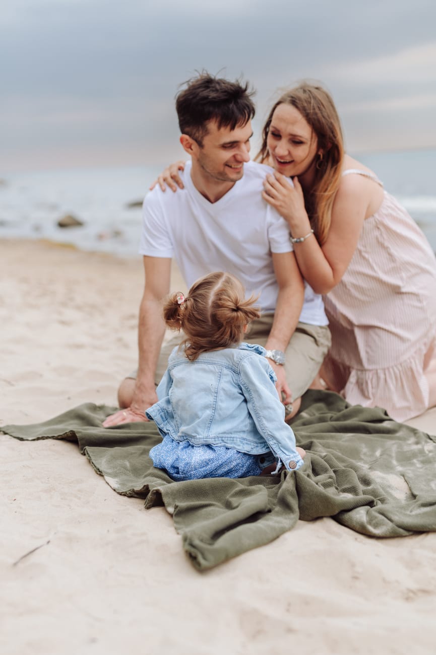 Córka patrzy na przytulonych rodziców sesja ciążowa