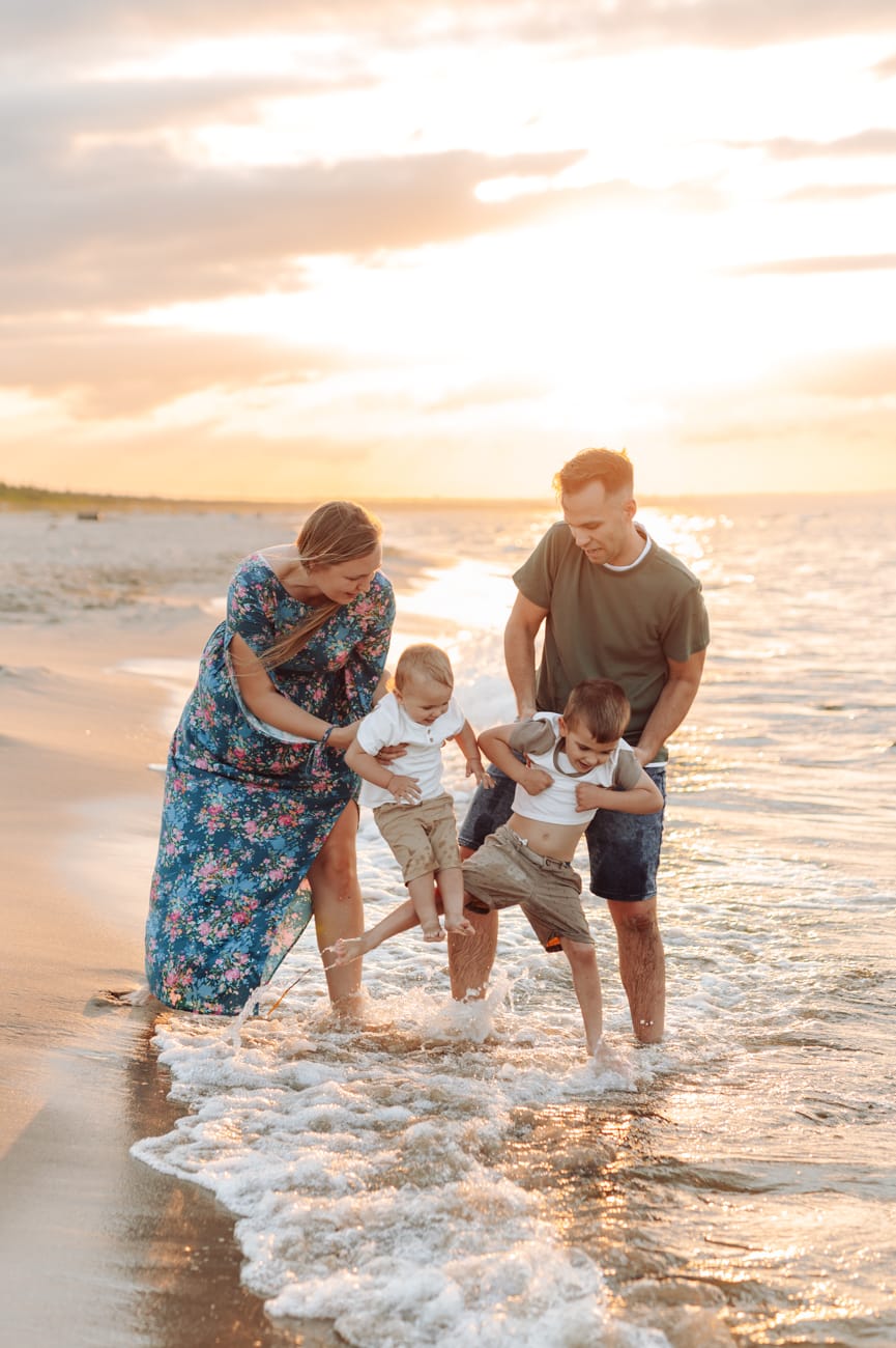 Chłopcy skaczący przez fale w promieniach zachodzącego słońca – dynamiczne ujęcie pełne energii.