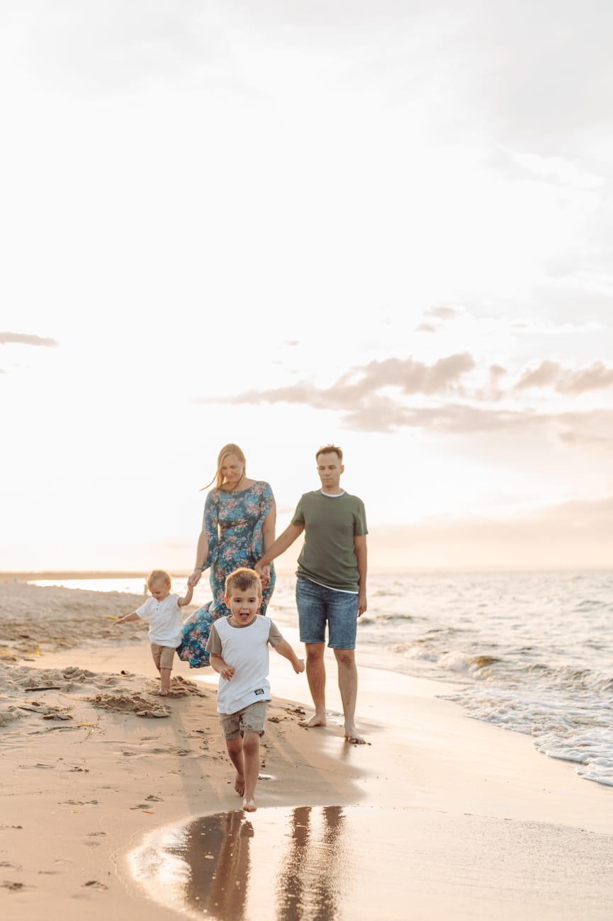Chłopiec biegnie po plaży zachód słońca sesja rodzinna
