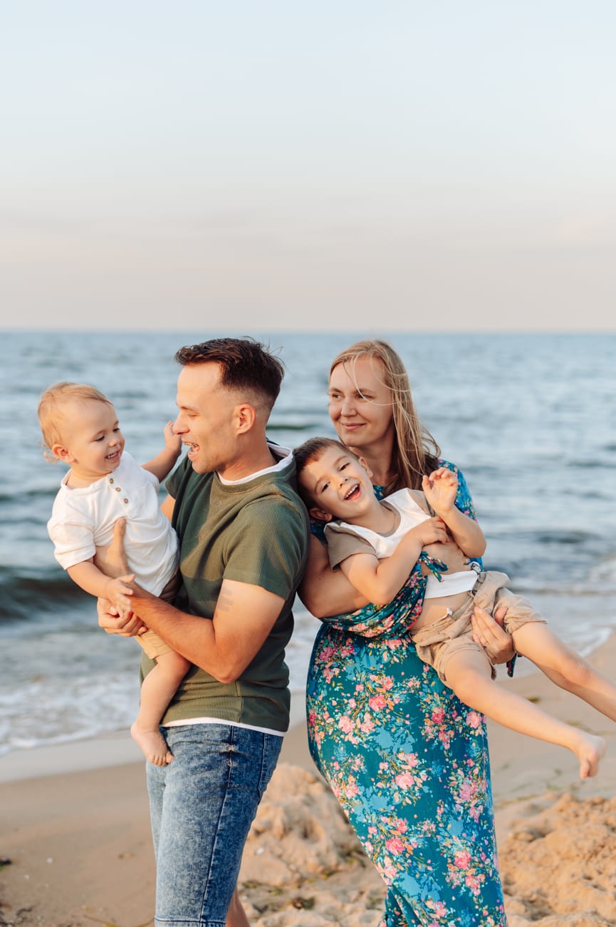 Radosny rodzinny kadr o zachodzie słońca na plaży.