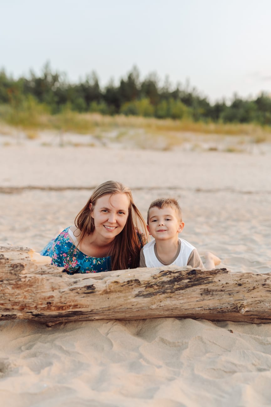 Mama z synem za pniem drzewa plaża sesja rodzinna