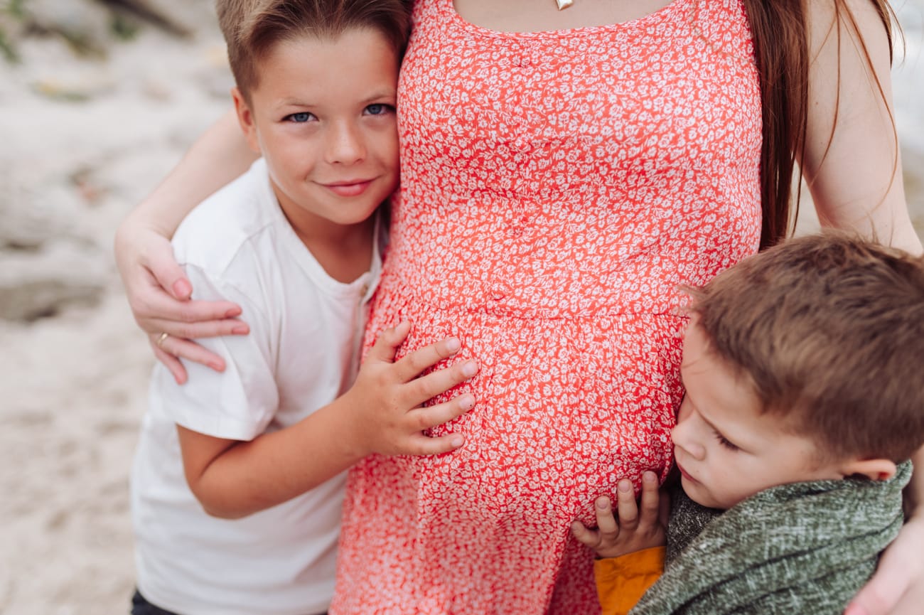 Ręce dzieci na brzuchu mamy sesja ciążowa nad morzem