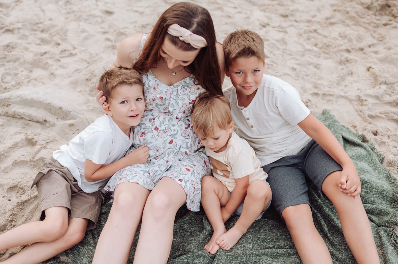Mama z trzema synami na kocu na plaży sesja ciążowa