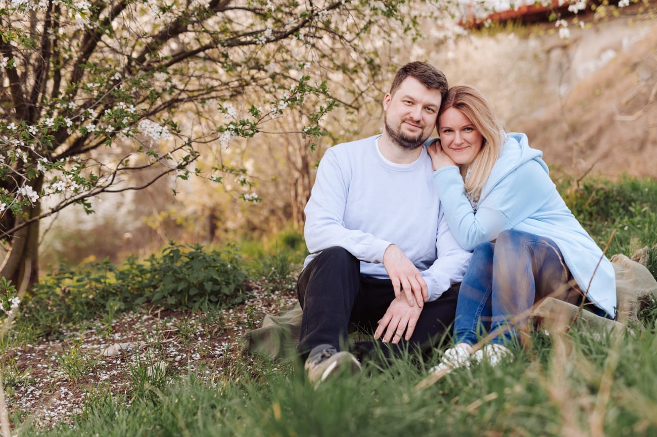 Rodzice na kocu pod kwitnącym drzewem sesja wiosenna