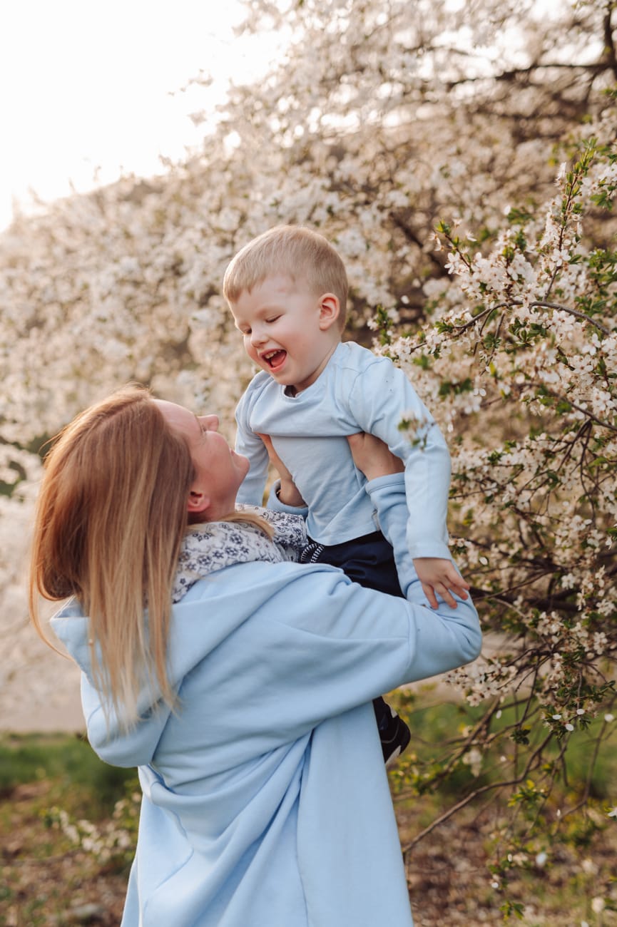 Mama podnosi syna kwitnące drzewa sesja wiosenna