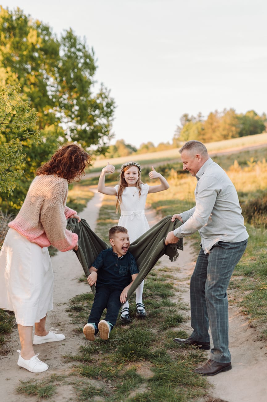 Rodzice huśtają syna w kocu plener komunijny