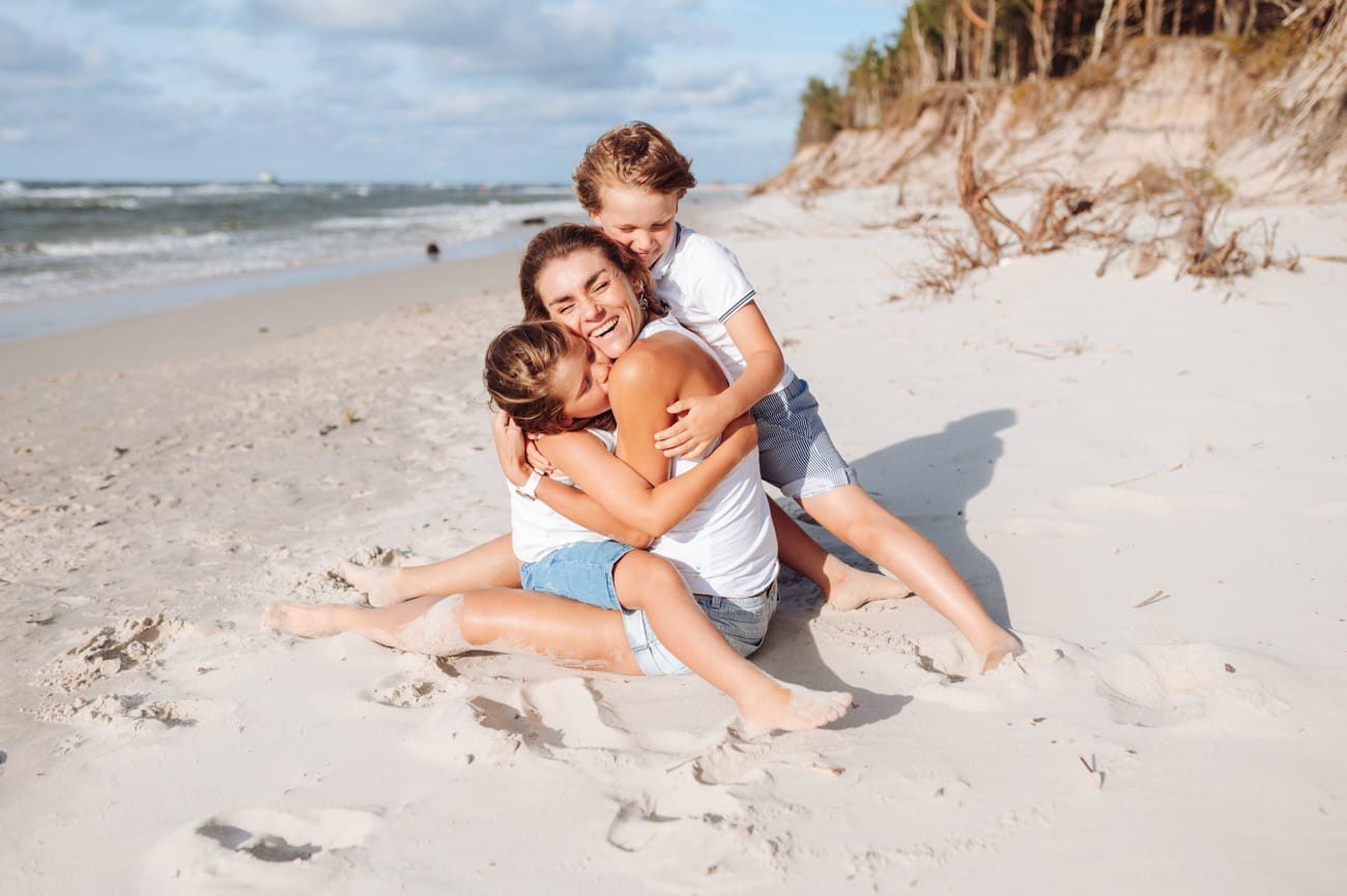 Mama przytulana przez dzieci sesja rodzinna na plaży
