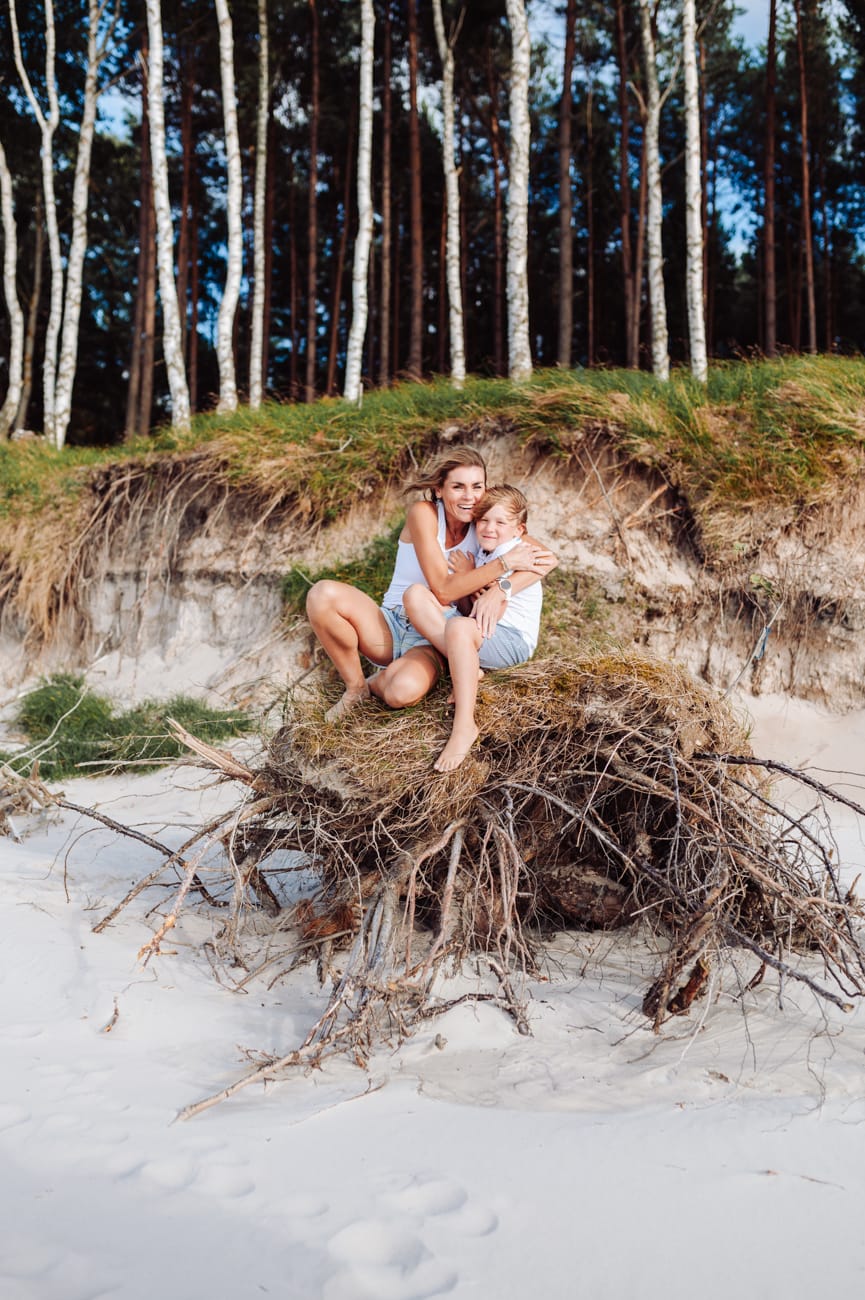 Mama z synem siedzą na korzeniach drzew sesja nad morzem