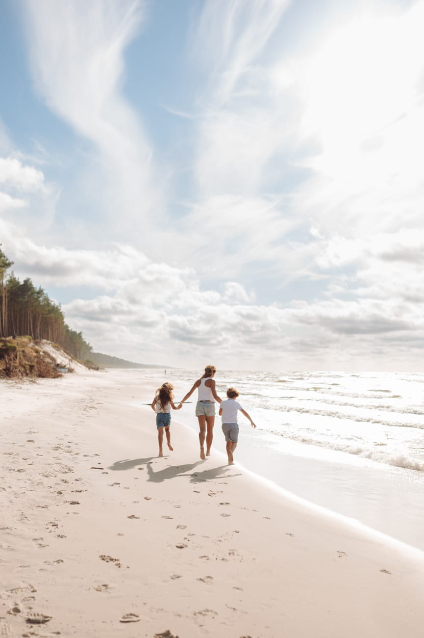 Bliźniak z mamą biegną po plaży sesja rodzinna