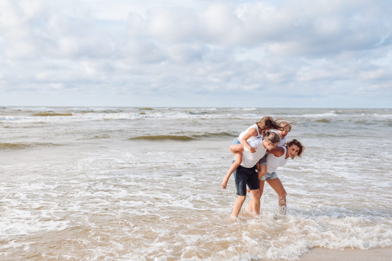 Rodzice z dziećmi na barana przepychaja się na brzegu morza