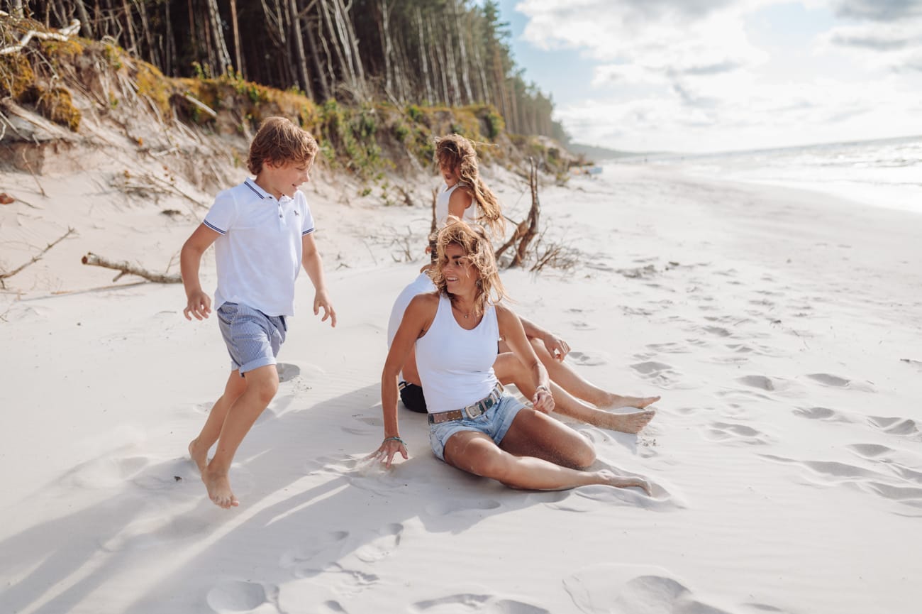 Dzieci biegają wkoło rodziców sesja rodzinna nad morzem