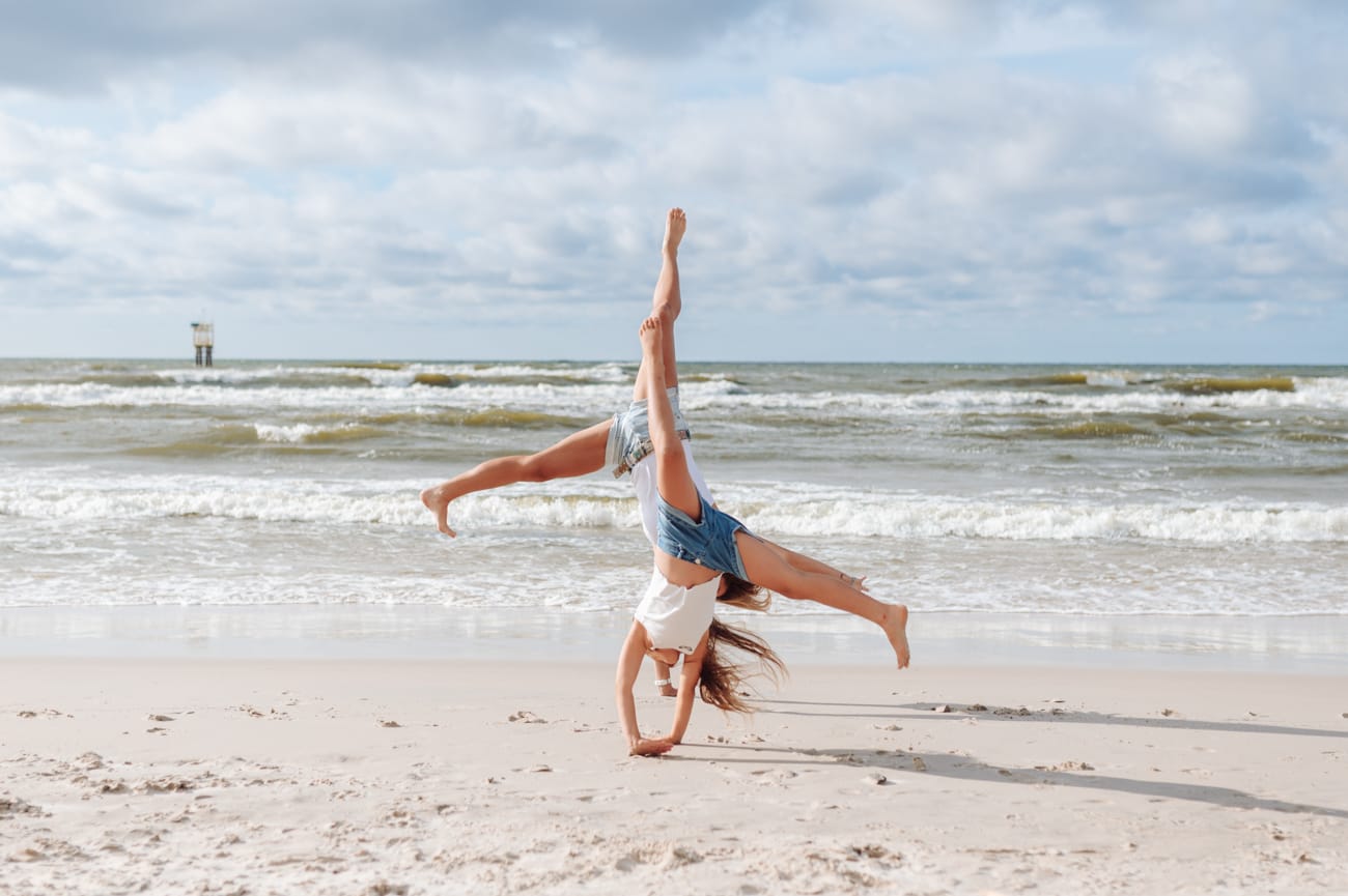 Córka z mamą robią gwiazdę na piasku sesja z dziećmi
