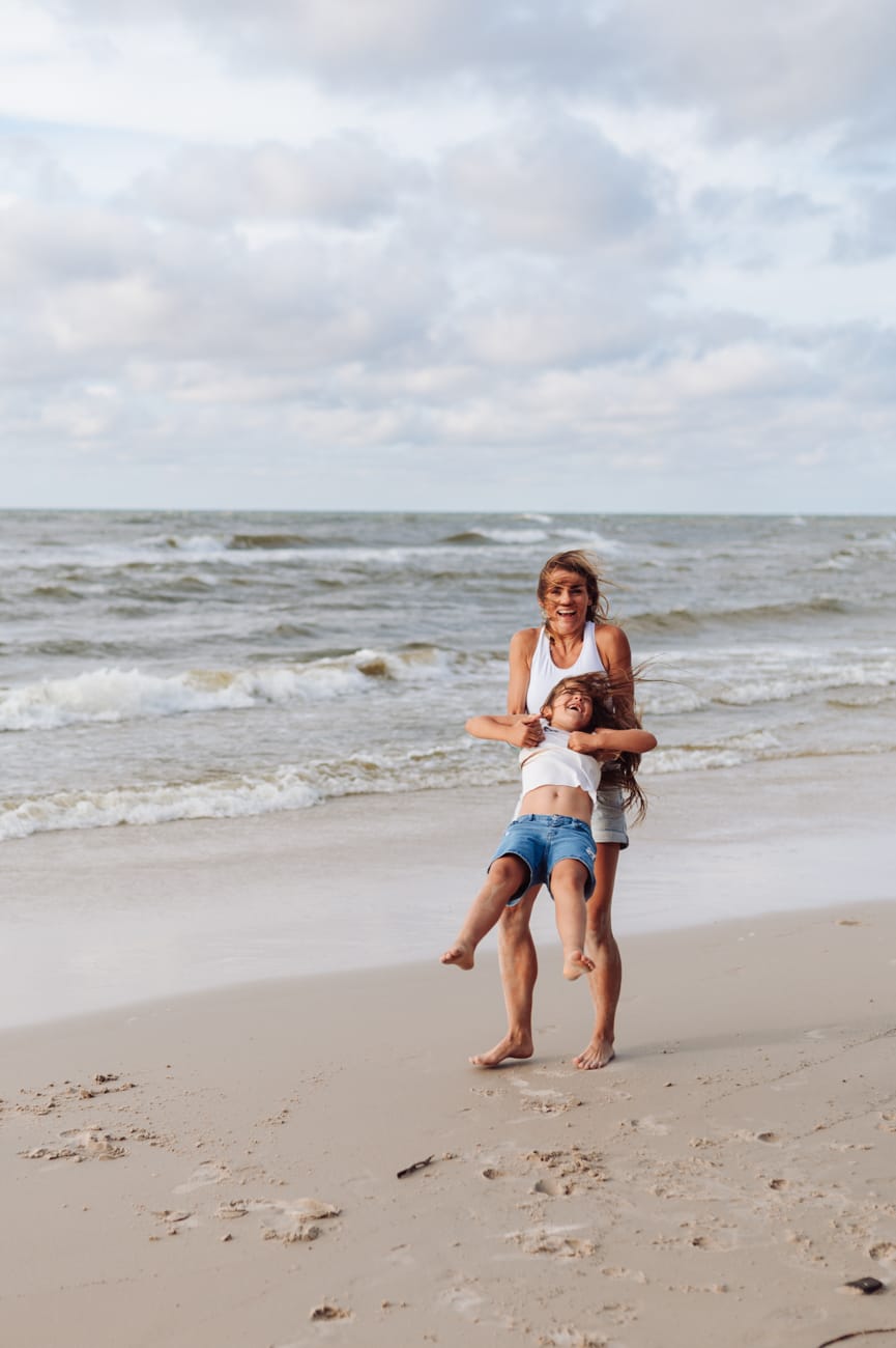 Mama z córką na brzegu morza kręcą się w kółko sesja rodzinna