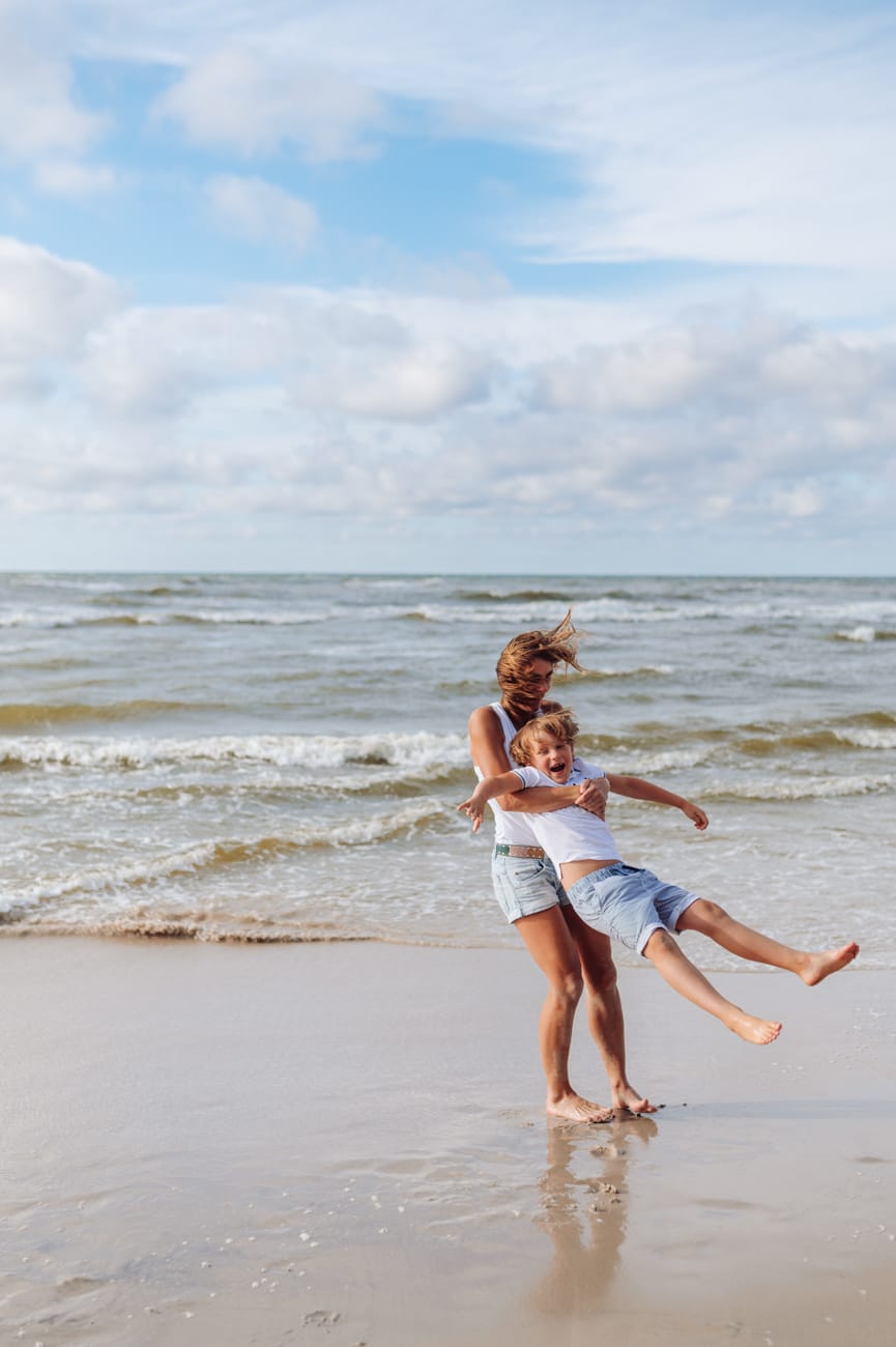 Mama z synem na brzegu morza kręcą się w kółko sesja rodzinna