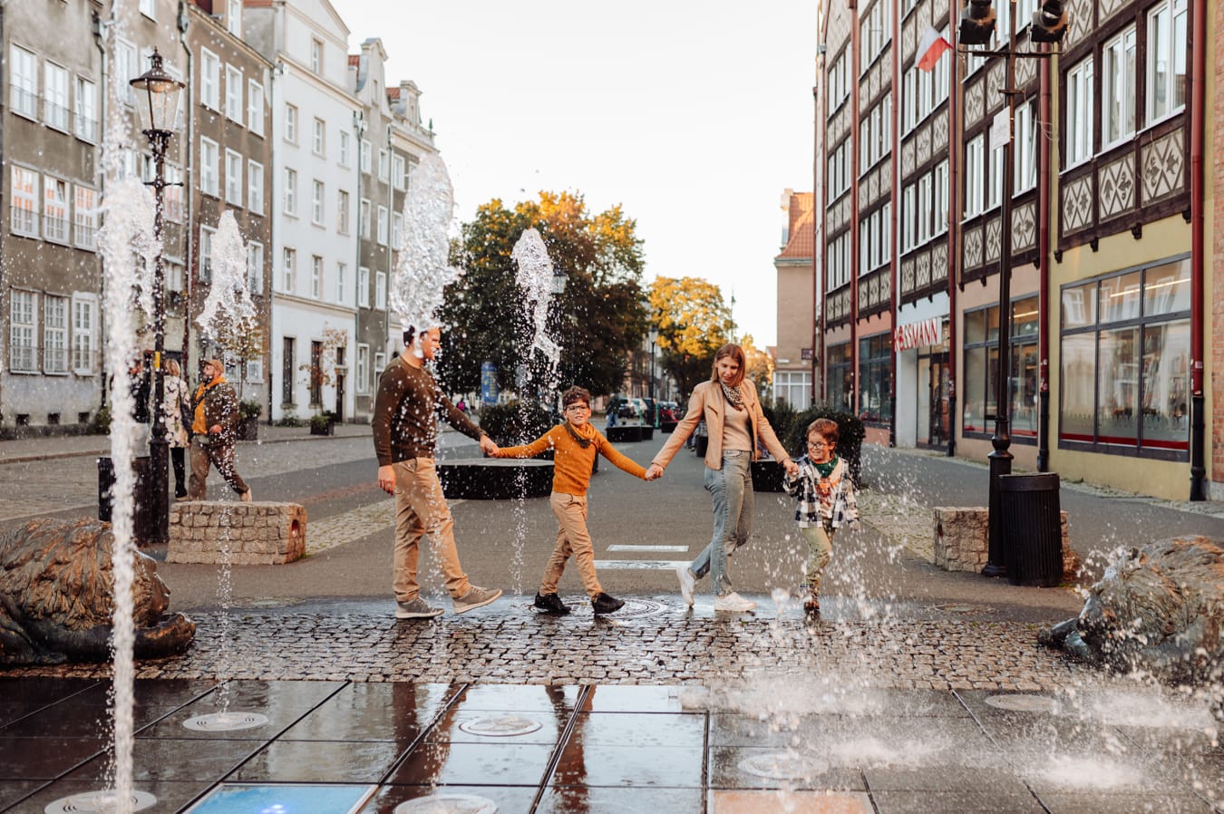 Rodzina przy fontannie na brukowanej uliczce sesja miejska Gdańsk