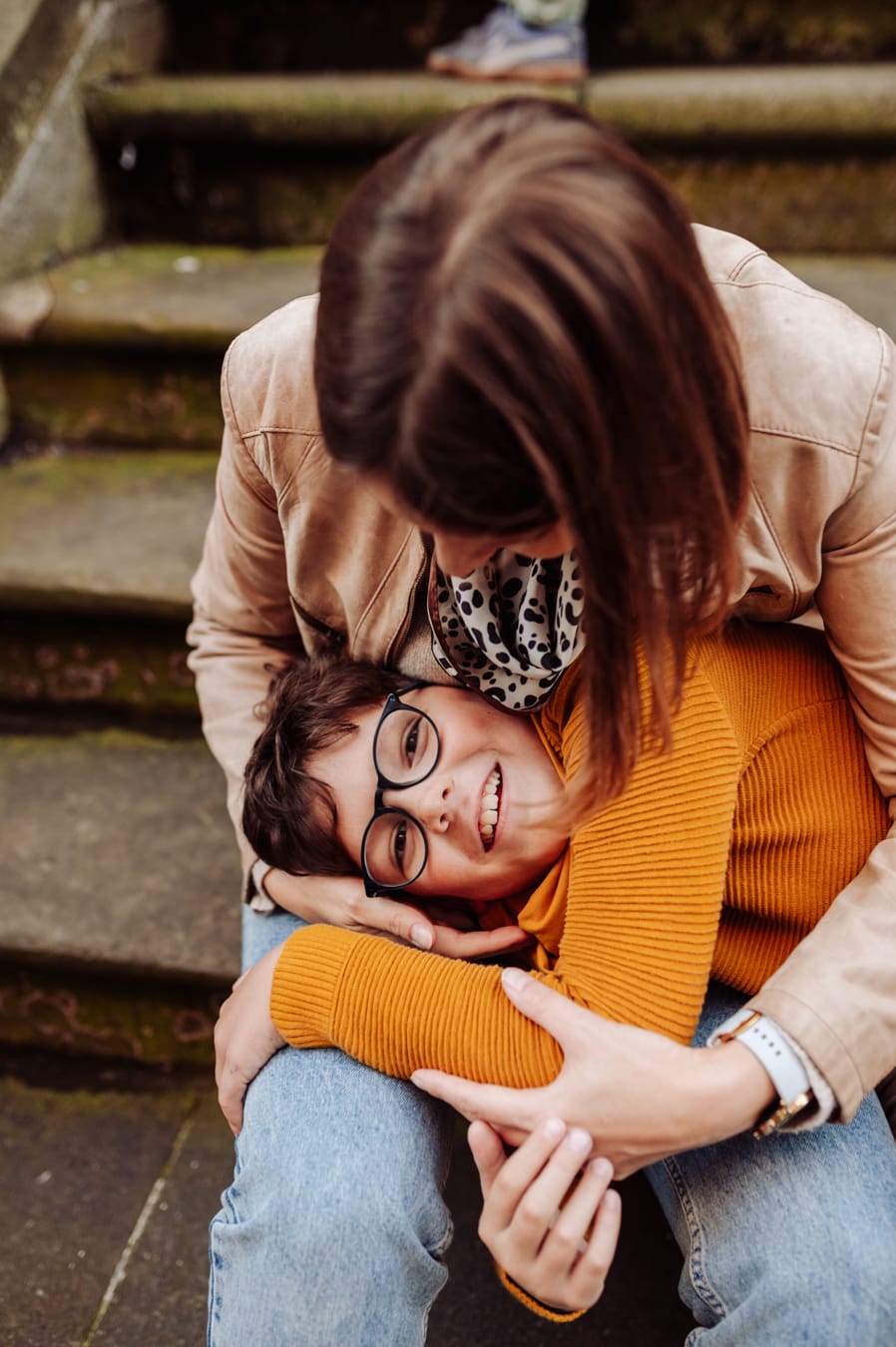 Mama przytula synka na tle schodów podczas miejskiej sesji z dziećmi na Starym Mieście