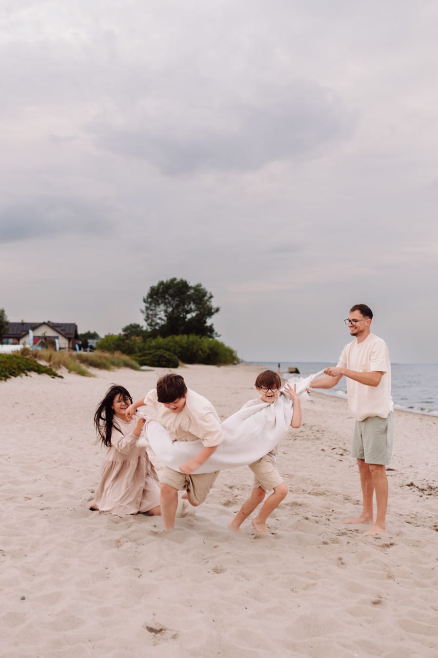 Nastolatek owinięty kocem na plaży portret sesja rodzinna
